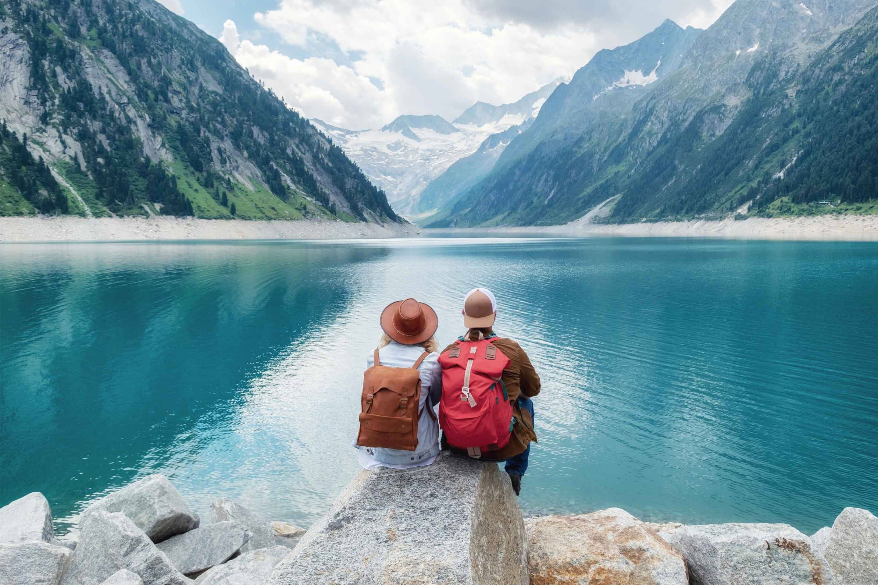 Ein Mann und eine Frau blicken auf eine typisch österreichische Gebirgsszene und freuen sich auf ihr neues Leben in Österreich.